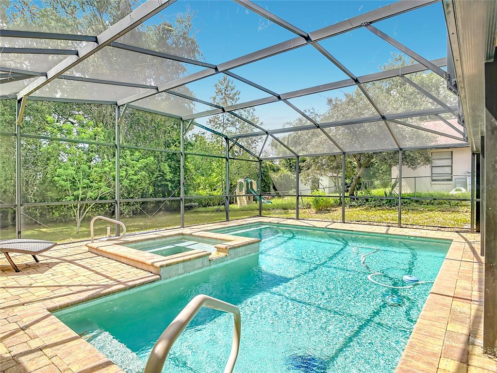 A swimming pool and attached hot tub sit on a patio enclosed by a screen cage — 3208 LAKE HELEN OSTEEN ROAD, DELTONA, FL