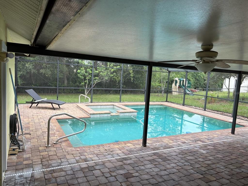 A swimming pool and attached hot tub sit on a patio enclosed by a screen cage — 3208 LAKE HELEN OSTEEN ROAD, DELTONA, FL