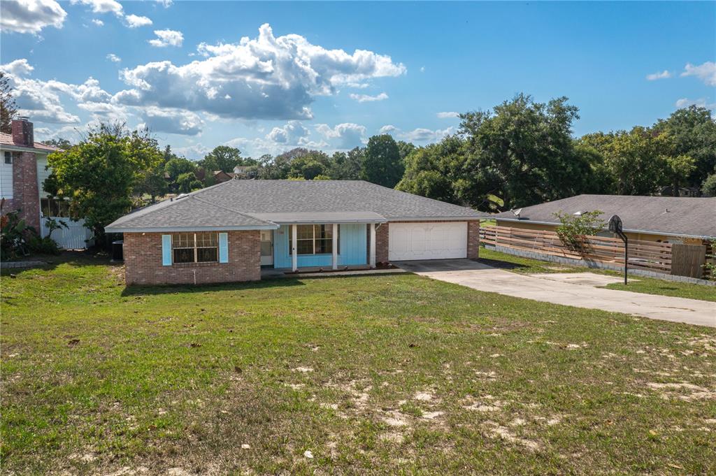 A single-story brick house with a blue-trimmed porch and an attached two-car garage — 136 LAKE RING DRIVE, WINTER HAVEN, FL