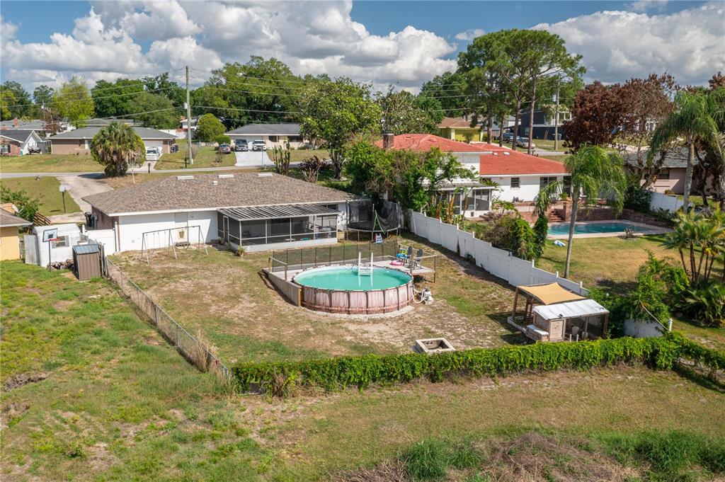 An aerial view shows a backyard with an above-ground pool, a screened patio, and fencing — 136 LAKE RING DRIVE, WINTER HAVEN, FL