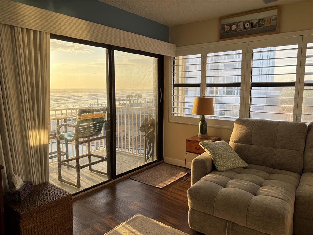 A living room with a sectional sofa, a table lamp, and a balcony overlooking the ocean — 1571 S ATLANTIC AVENUE UNIT 307, NEW SMYRNA BEACH, FL