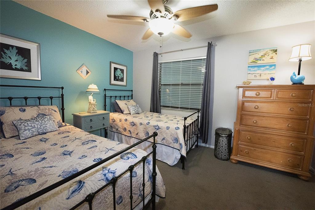 A bedroom features two twin beds with seashell-patterned quilts, a wooden dresser, and blue walls — 1571 S ATLANTIC AVENUE UNIT 307, NEW SMYRNA BEACH, FL
