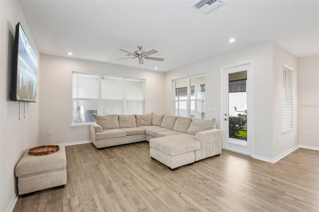A living room features light wood-look flooring, a large beige sectional sofa, and a ceiling fan — 13690 STEVENSON LANE, ODESSA, FL
