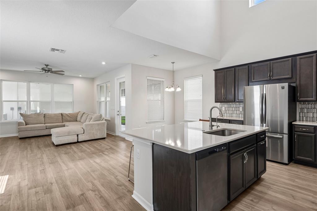 An open-concept kitchen with dark cabinets and a white island overlooks a living room area — 13690 STEVENSON LANE, ODESSA, FL