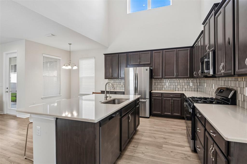 A kitchen features dark wood cabinets, a large island with a sink, and stainless steel appliances — 13690 STEVENSON LANE, ODESSA, FL