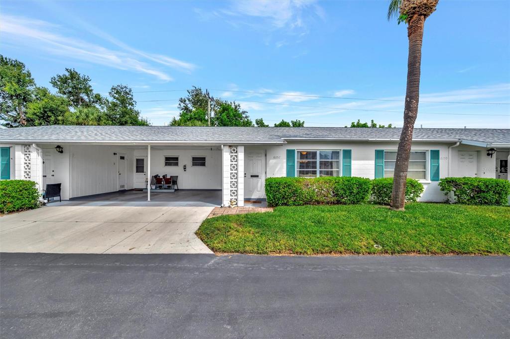 A single-story residential building features a carport, white siding, and green shutters — 6057 CORAL WAY UNIT 3, BRADENTON, FL