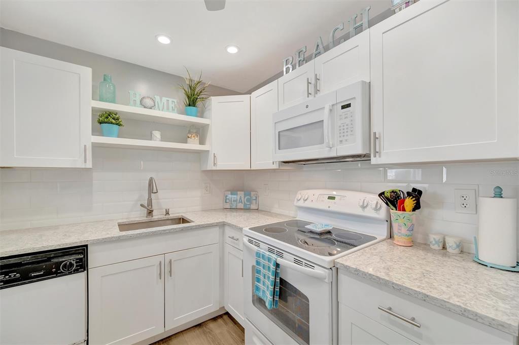 A living room and dining area with light green walls, tile floors, and coastal decor — 6057 CORAL WAY UNIT 3, BRADENTON, FL