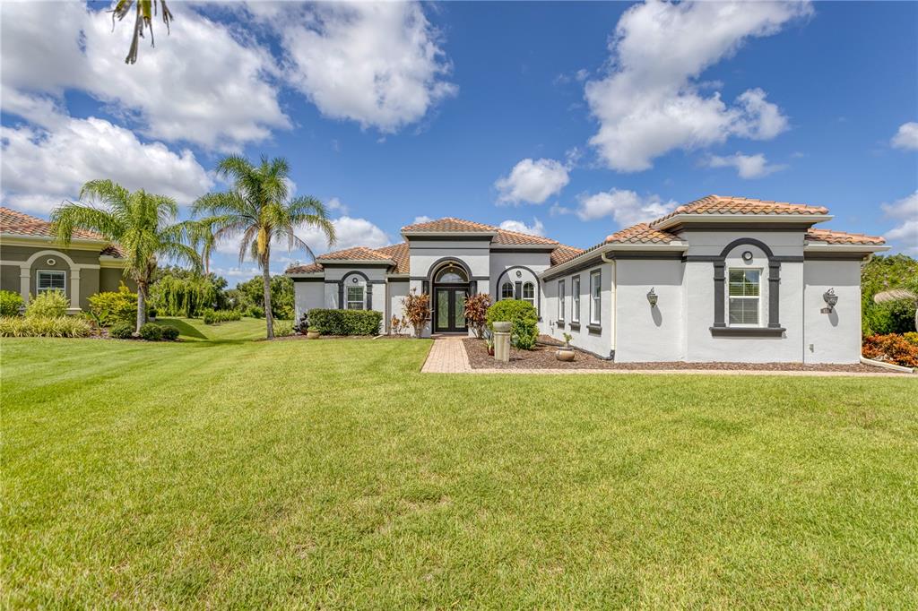 A single-story stucco house with a tile roof and a brick walkway in Florida — 614 165TH STREET E, BRADENTON, FL
