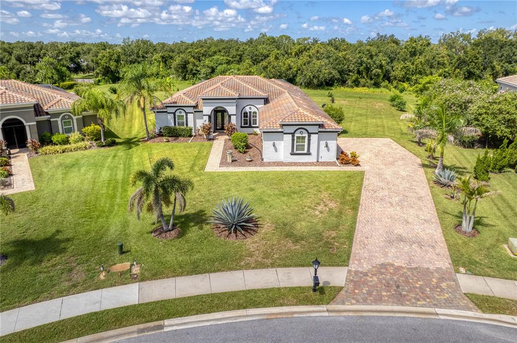 An aerial view of a single-story house with a tiled roof and brick paver driveway — 614 165TH STREET E, BRADENTON, FL