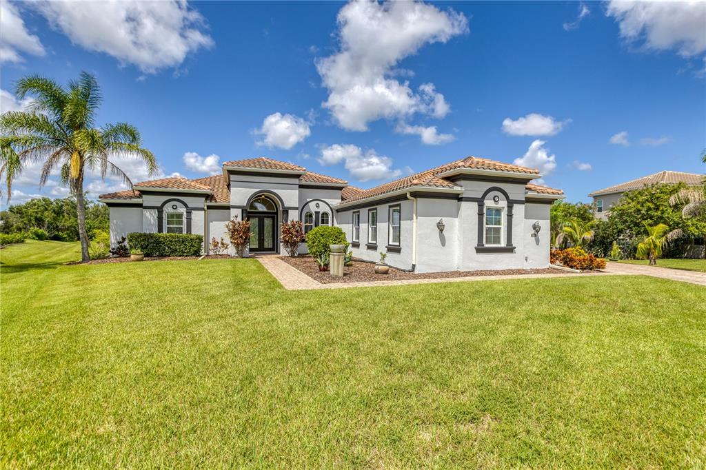 A single-story house with a tiled roof, white stucco exterior, and a manicured lawn — 614 165TH STREET E, BRADENTON, FL