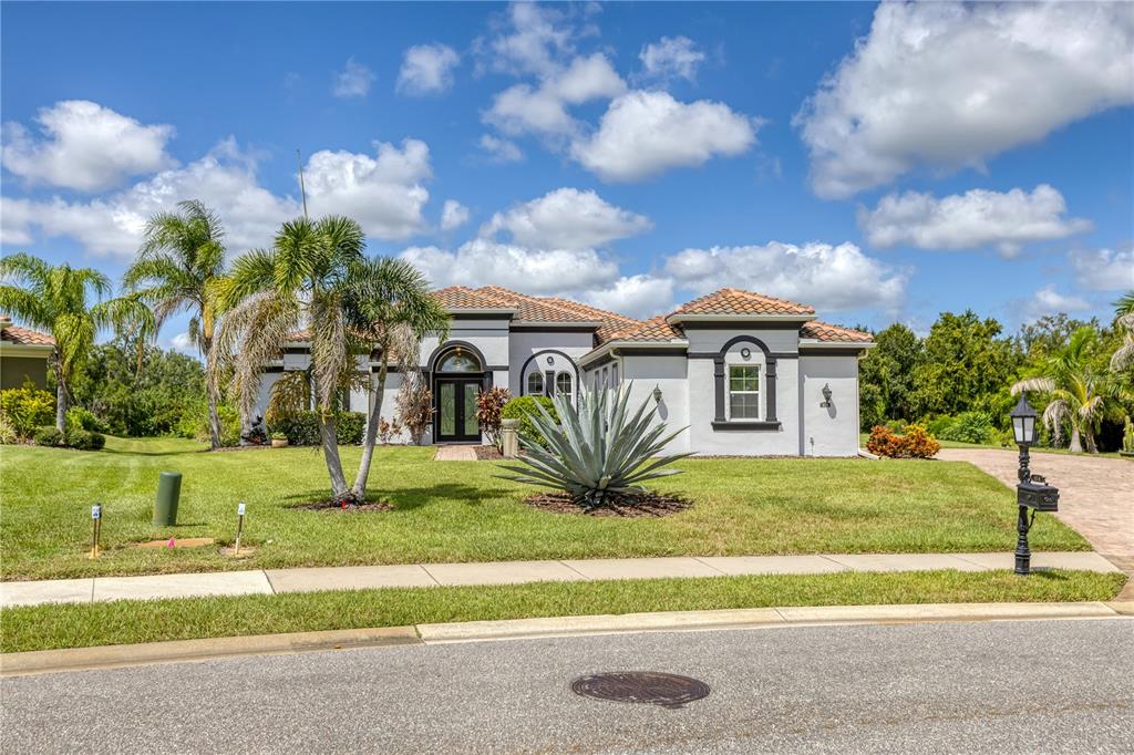 A single-story house with a tile roof, gray stucco exterior, and a large front yard — 614 165TH STREET E, BRADENTON, FL