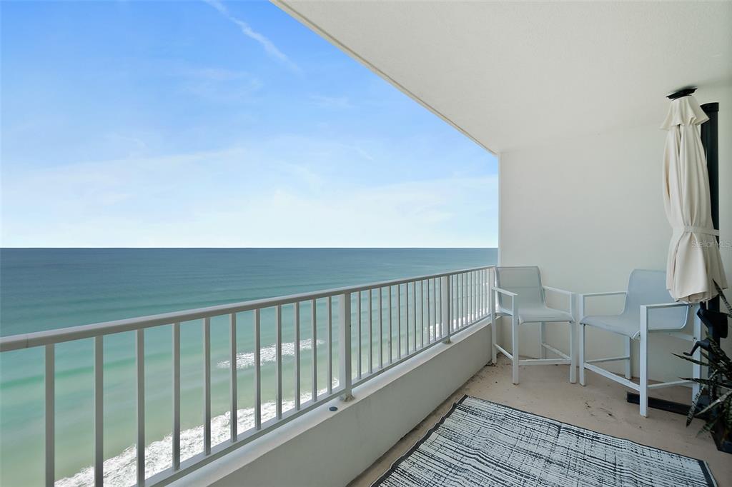 A balcony with white railings overlooks the ocean and features two chairs and an umbrella — 2937 S ATLANTIC AVENUE UNIT 1905, DAYTONA BEACH SHORES, FL