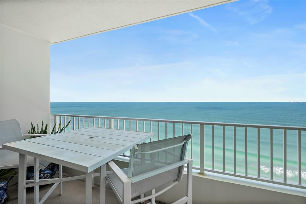 A balcony with a white table and chairs overlooks the ocean under a blue sky — 2937 S ATLANTIC AVENUE UNIT 1905, DAYTONA BEACH SHORES, FL
