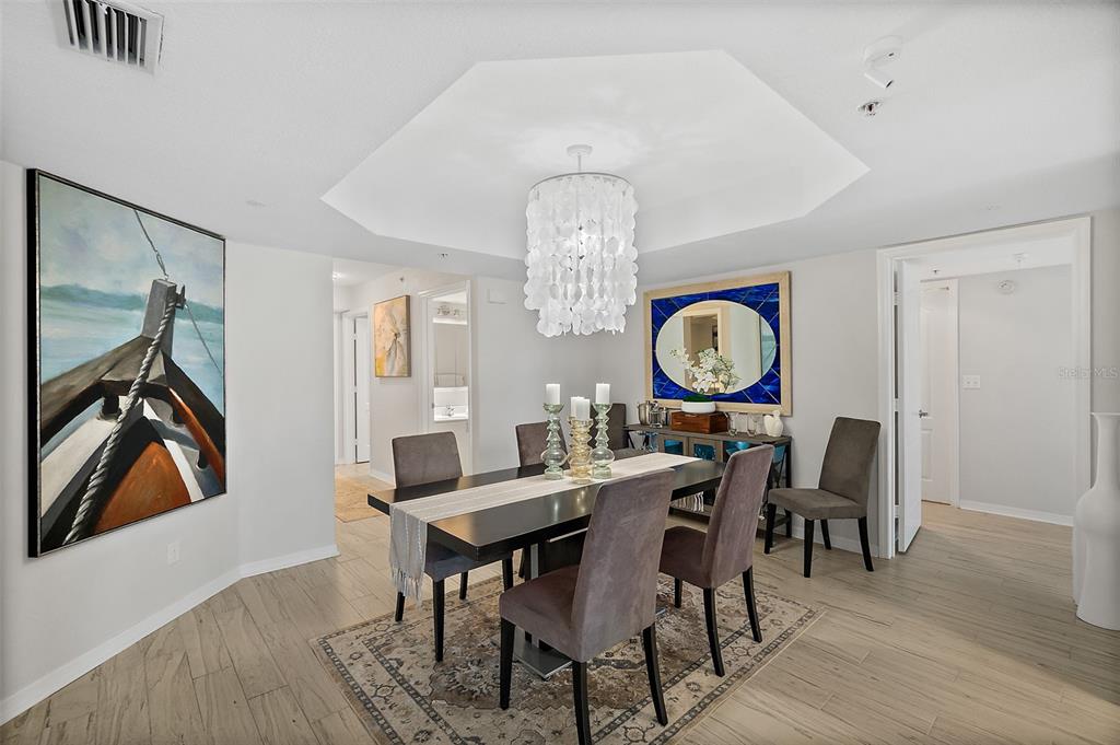 A dining room features a dark table, upholstered chairs, a capiz shell chandelier, and artwork — 2937 S ATLANTIC AVENUE UNIT 1905, DAYTONA BEACH SHORES, FL