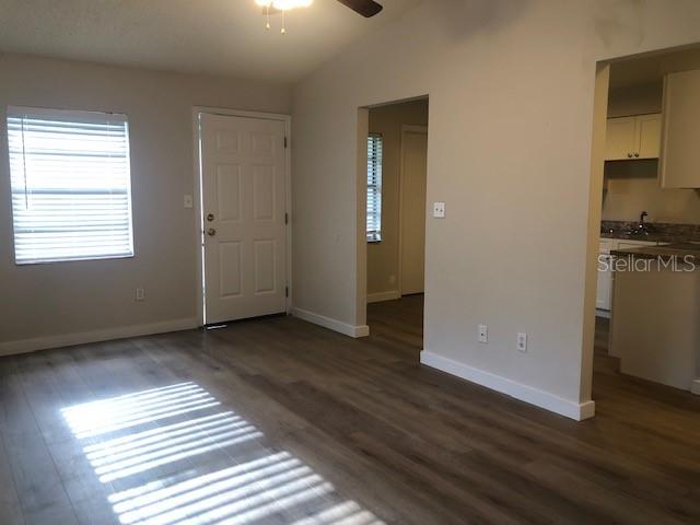 An interior view of a living area with wood-look flooring, a front door, and kitchen — 2419 CEDAR AVENUE UNIT B, SANFORD, FL