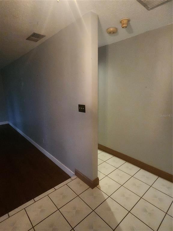 A hallway features a transition from dark wood flooring to white tile with a partition wall — 8104 GRANADA BOULEVARD, ORLANDO, FL