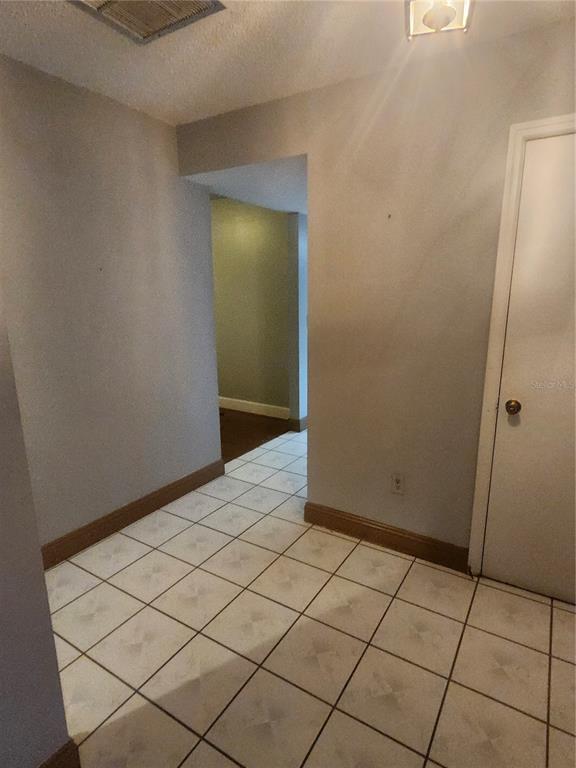 A tiled hallway leads to an adjacent room with wood flooring and light green walls — 8104 GRANADA BOULEVARD, ORLANDO, FL