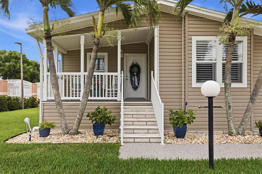 The exterior of a tan mobile home features a front porch, stairs, and palm trees — 3530 70TH AVENUE E, ELLENTON, FL