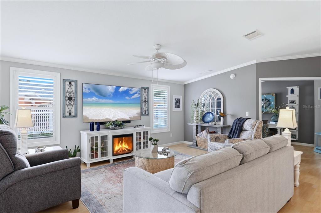A living room features a fireplace console, a large television, and light gray walls — 3530 70TH AVENUE E, ELLENTON, FL