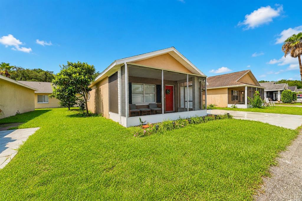 A single-story house with a screened-in front porch and a green lawn under a blue sky — 4772 SILVER CIRCLE, ZEPHYRHILLS, FL