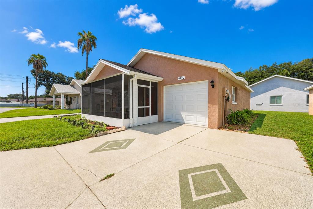 A single-story house with a screened-in porch, a white garage door, and a concrete driveway — 4772 SILVER CIRCLE, ZEPHYRHILLS, FL