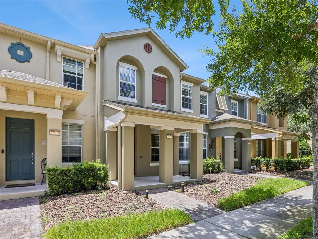 A row of two-story townhouses with tan stucco siding, covered porches, and paved walkways — 7712 FORDSON LANE, WINDERMERE, FL