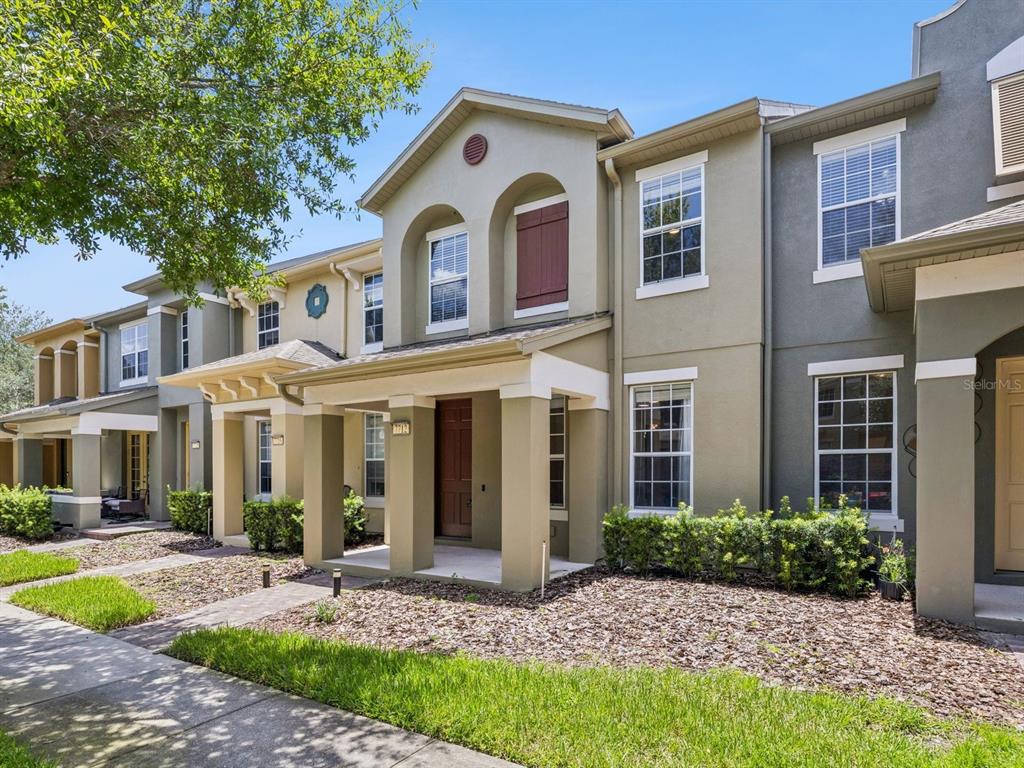 A row of two-story townhomes with tan stucco facades, covered porches, and brown shutters — 7712 FORDSON LANE, WINDERMERE, FL