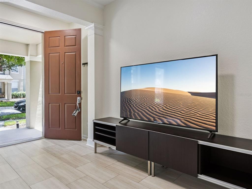 A living room features a television on a dark media console near an open door — 7712 FORDSON LANE, WINDERMERE, FL