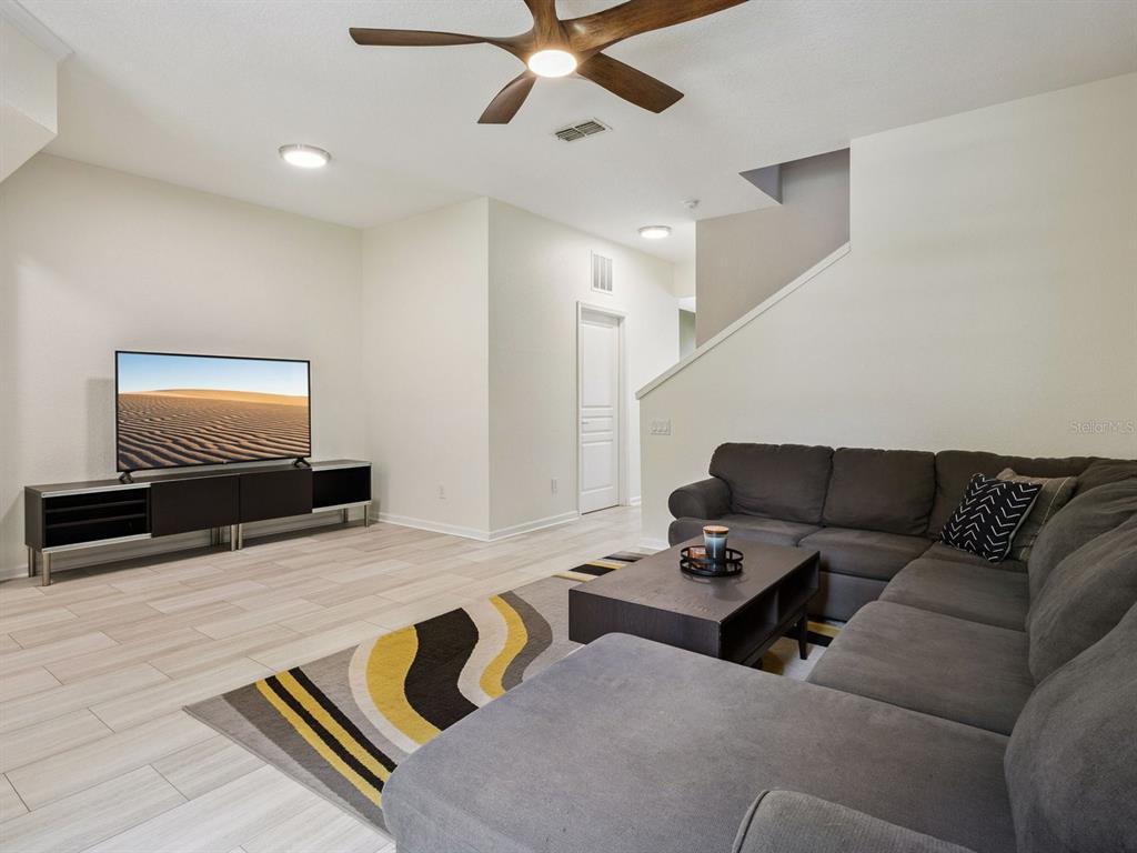 A living room features a gray sectional sofa, a television on a stand, and tile flooring — 7712 FORDSON LANE, WINDERMERE, FL