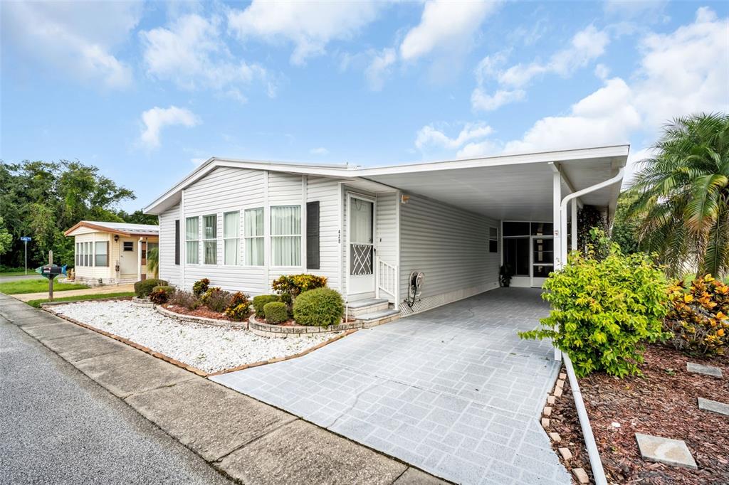 A light-colored mobile home features a carport, a white gravel garden, and a paved driveway — 428 PELICAN DRIVE S, OLDSMAR, FL