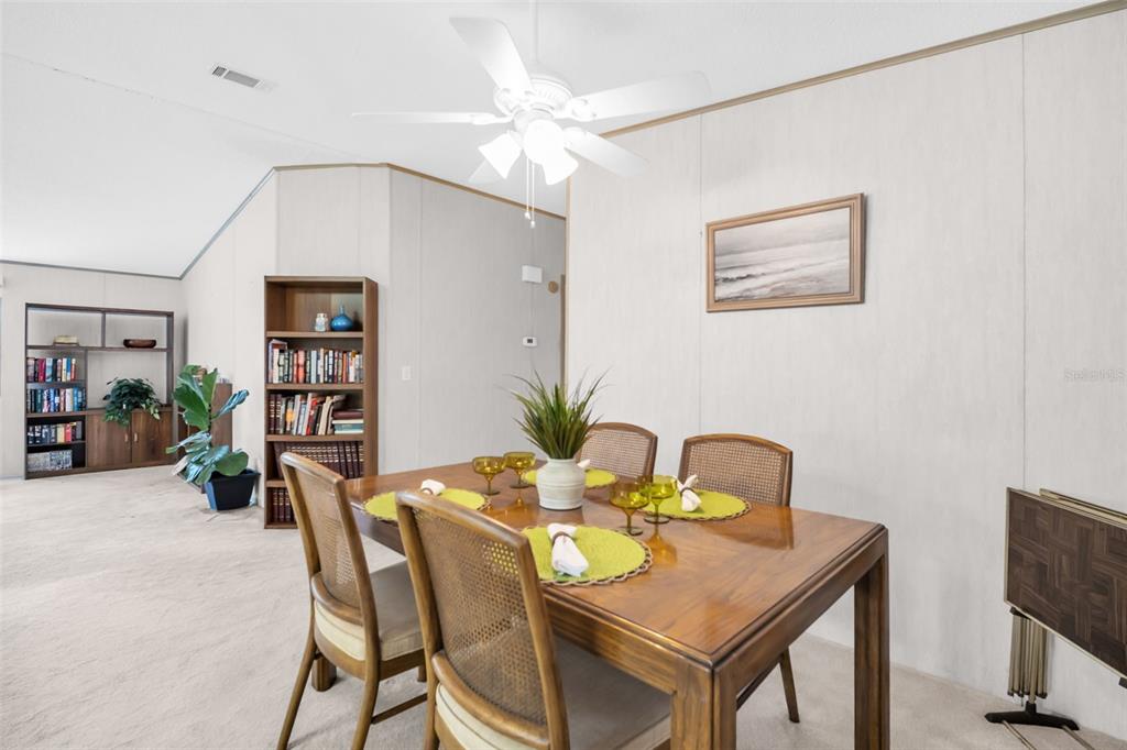 A dining area features a wooden table with four chairs, a ceiling fan, and bookshelves — 428 PELICAN DRIVE S, OLDSMAR, FL