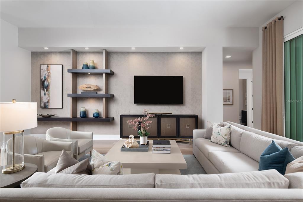 A modern living room features a wall-mounted television, built-in shelving, and neutral-toned furniture — 3120 SW 108TH WAY, GAINESVILLE, FL