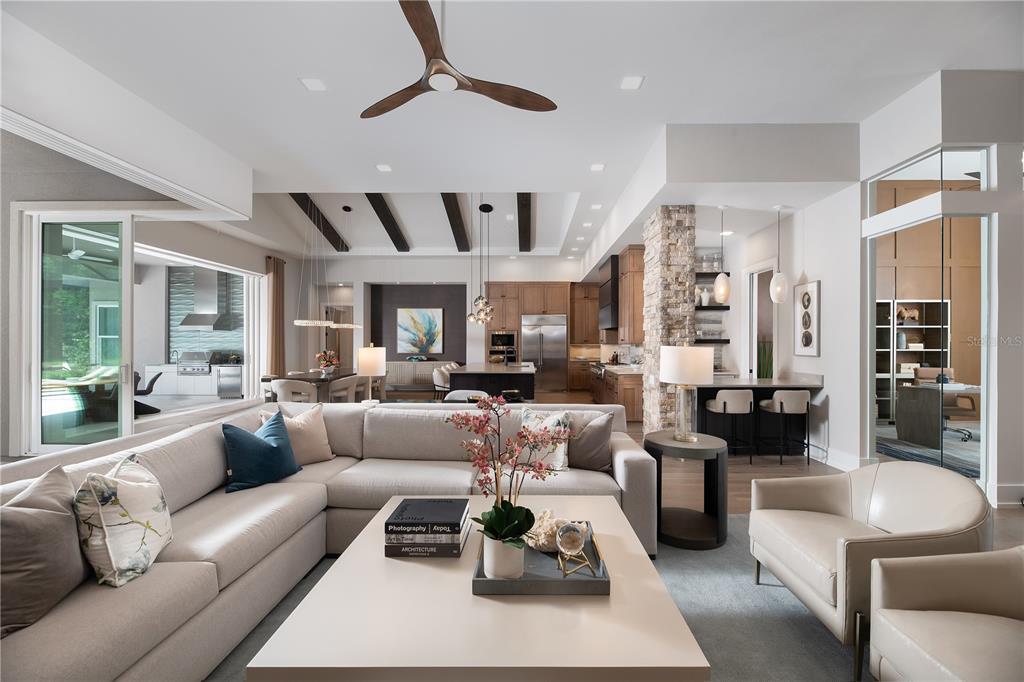 A modern open-concept living room features a large sectional sofa, coffered ceiling, and stone pillar — 3120 SW 108TH WAY, GAINESVILLE, FL