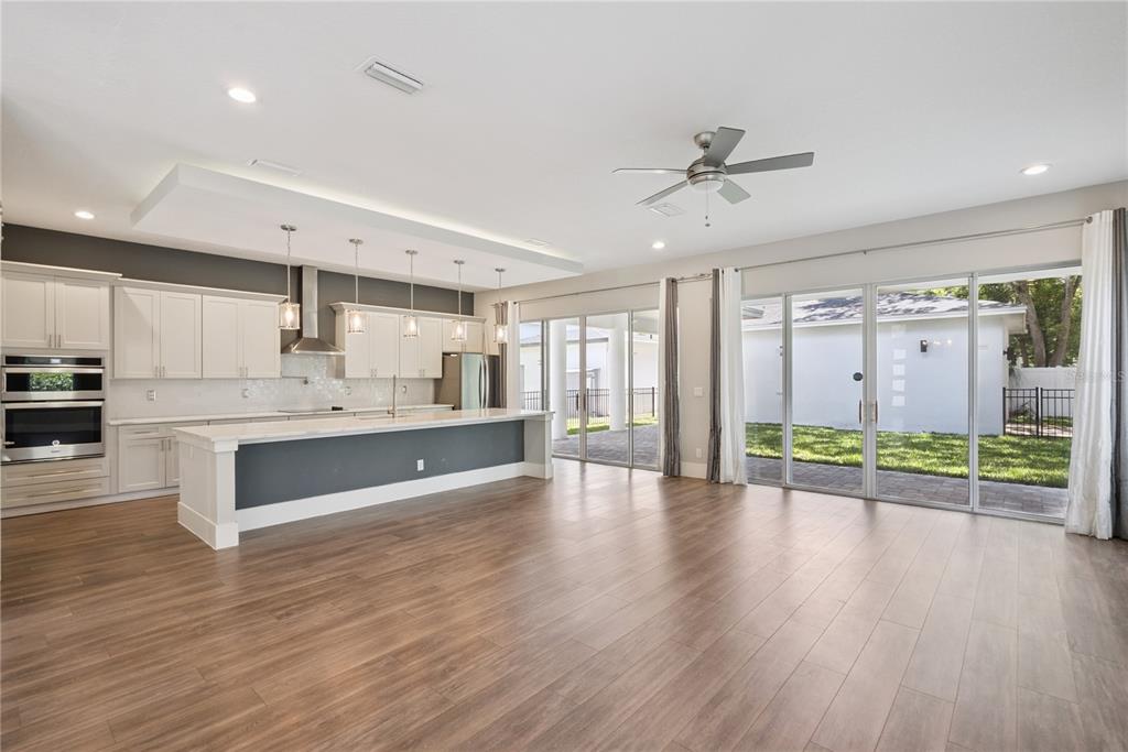 A modern kitchen with white cabinetry and a large island opens to a backyard patio — 200 E GRANT STREET, ORLANDO, FL