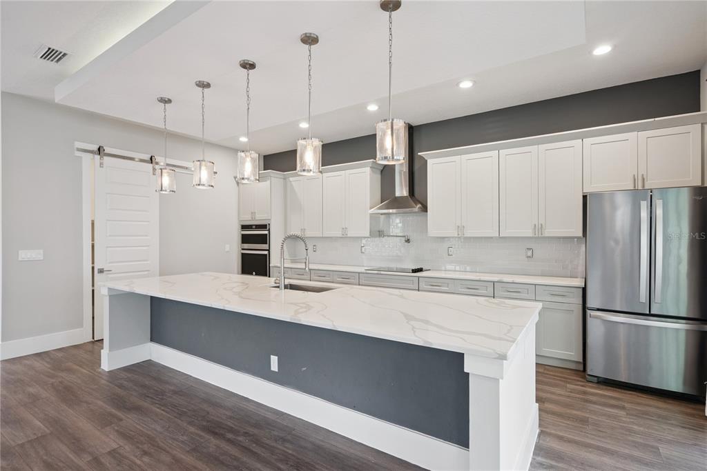 A modern kitchen features a large white marble island, gray cabinetry, and stainless steel appliances — 200 E GRANT STREET, ORLANDO, FL