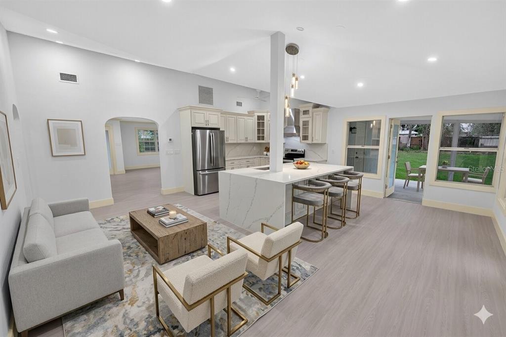 An open-concept living room and kitchen with light wood flooring, white cabinetry, and a central island — 870 NARCISSUS AVENUE, CLEARWATER BEACH, FL