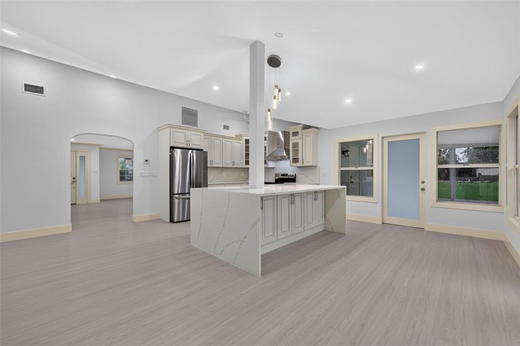 A kitchen with a large quartz island, stainless steel appliances, and light wood-look flooring — 870 NARCISSUS AVENUE, CLEARWATER BEACH, FL
