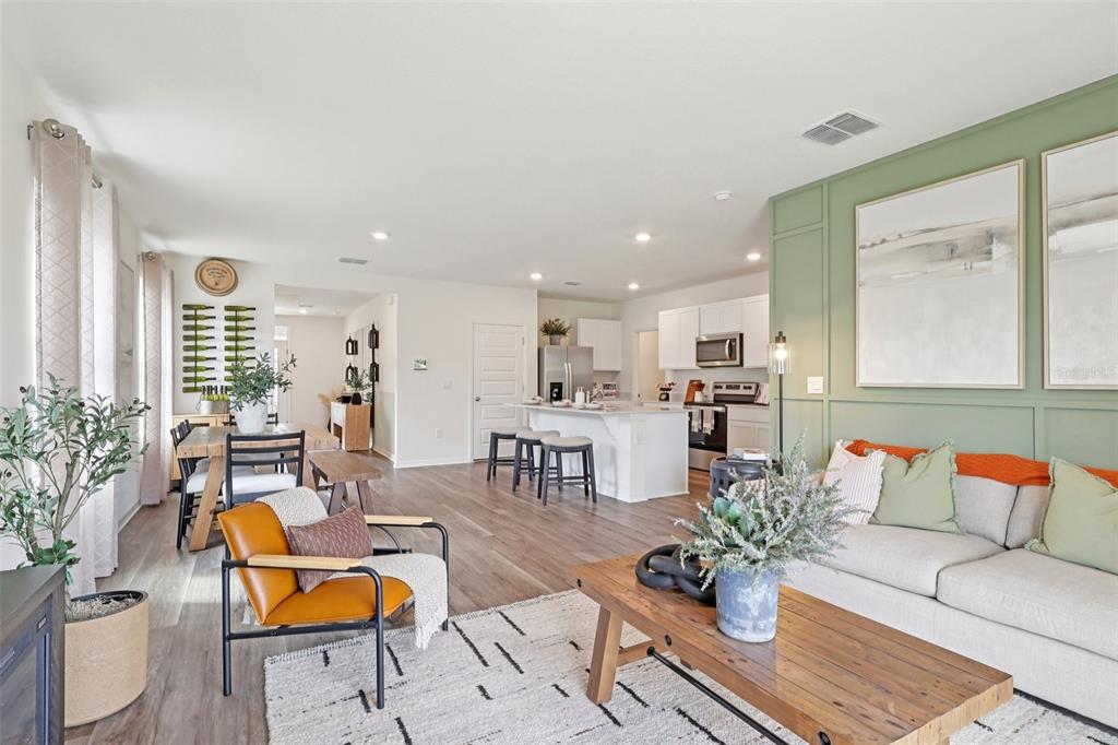 An open-concept living room and kitchen featuring light wood floors and a green accent wall — 4225 BIXBY BRIDGE PLACE, DAVENPORT, FL