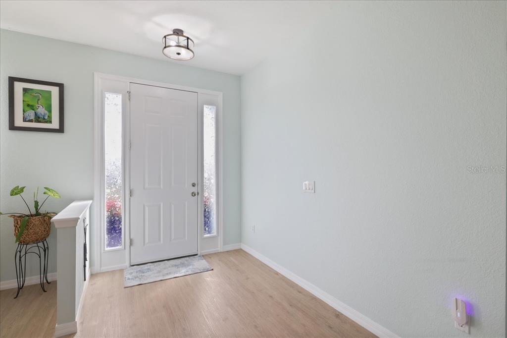 An entryway features light wood flooring, a white front door with sidelights, and pale walls — 8 ABAFT PLACE, PLACIDA, FL