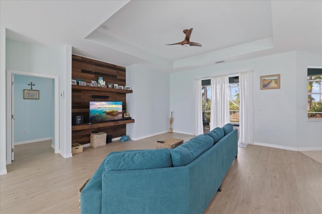 A living room features a blue sofa, a wood-paneled accent wall, and a tray ceiling — 8 ABAFT PLACE, PLACIDA, FL