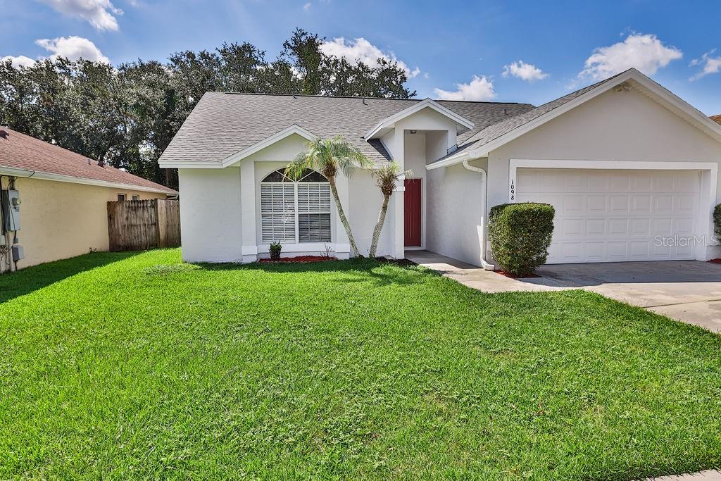 A single-story house with a white exterior, a two-car garage, and a front lawn — 1098 SUGARBERRY TRAIL, OVIEDO, FL
