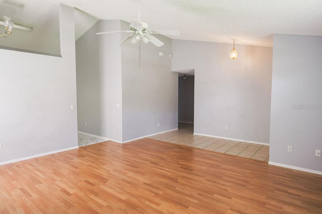 A living room with light gray walls, wood-look flooring, a ceiling fan, and tiled entryway — 1098 SUGARBERRY TRAIL, OVIEDO, FL