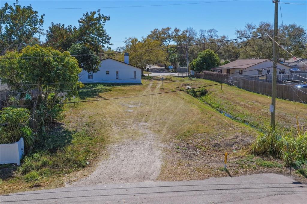 An elevated view shows a vacant, grassy lot with a dirt driveway and a drainage ditch — BRAGINTON STREET, LARGO, FL