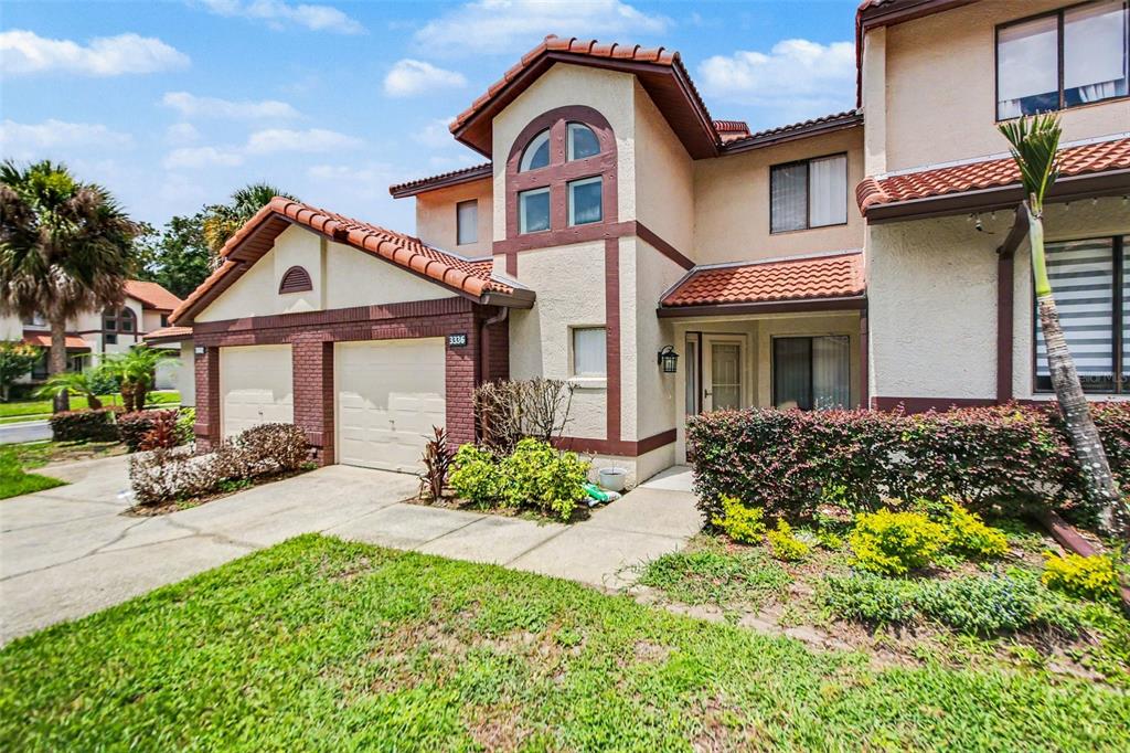 A two-story townhouse with a two-car garage, stucco exterior, and a red tile roof — 3336 GRAY FOX COVE UNIT 3336, APOPKA, FL