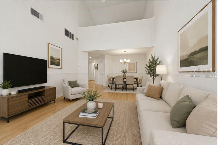 A living room with high ceilings, light wood floors, and an adjacent dining area — 3336 GRAY FOX COVE UNIT 3336, APOPKA, FL