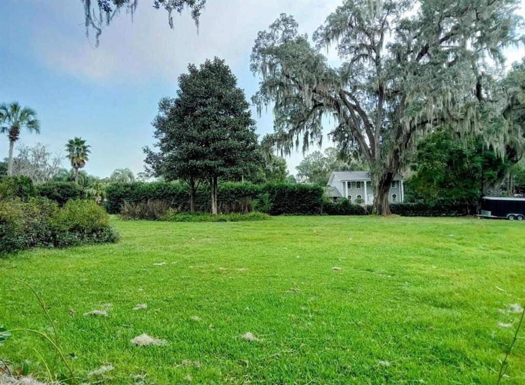 A large, grassy lot features mature trees with Spanish moss and a distant house — 0 SE 12TH STREET N, OCALA, FL
