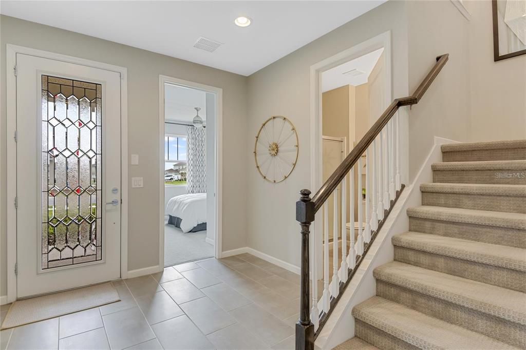 An entryway features a tiled floor, a staircase with carpeted steps, and a glass-paneled door — 10113 TURNBERRY LANE, LEESBURG, FL