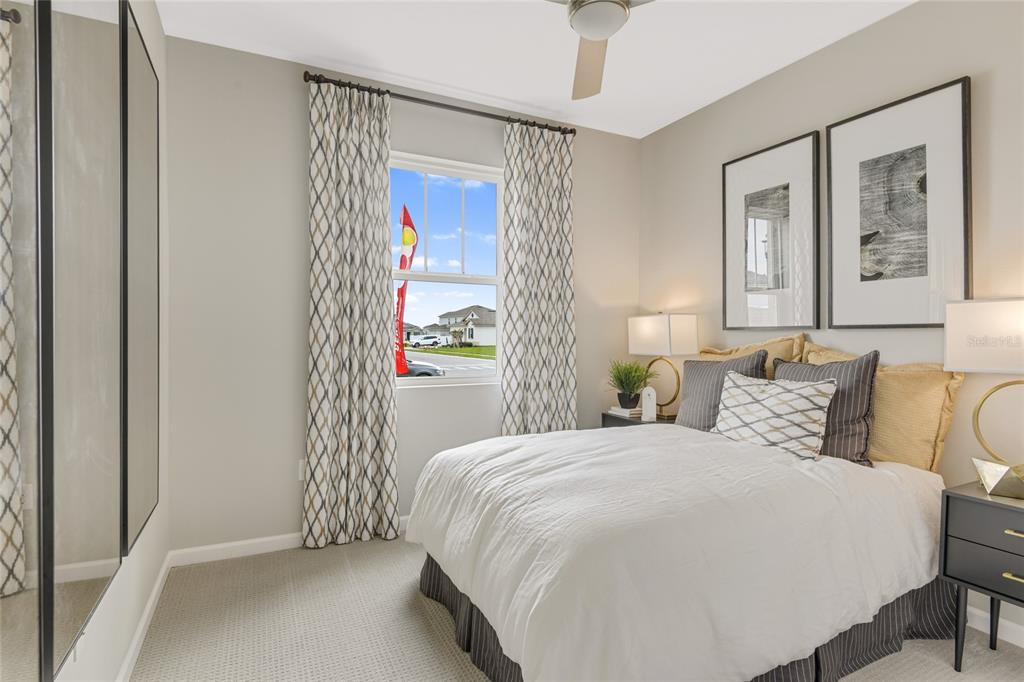 A bedroom features a bed with white bedding, patterned curtains, and two framed wall prints — 10113 TURNBERRY LANE, LEESBURG, FL