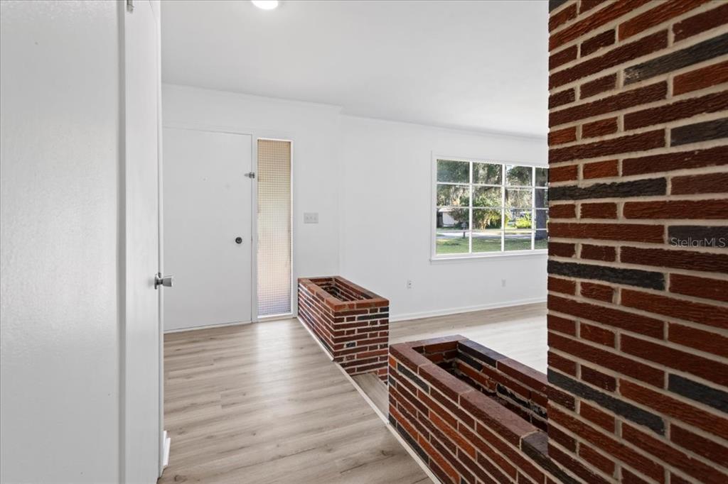 An entryway with light wood flooring, a white door, and decorative brick planter boxes — 2107 GOLF DRIVE, PALATKA, FL