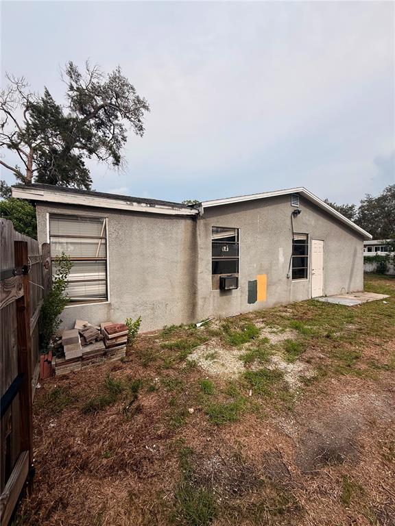 The exterior of a single-story house with stucco walls, two windows, and a white door — 806 W SHELL POINT ROAD, RUSKIN, FL